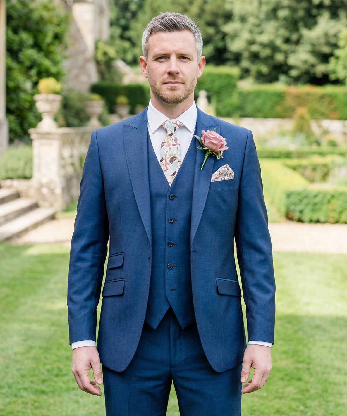Groom wearing a French navy mohair 3-piece lounge suit for a wedding or formal event, crafted from lightweight, smooth fabric with subtle sheen; includes tailored jacket, waistcoat, tie and pocket square, available to hire or buy from Black Tie Menswear.